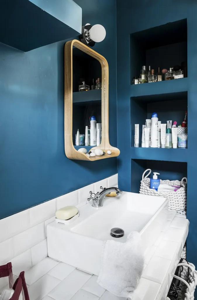 Salle de bain d'appartement rénové, mur bleu et carreau en porcelaine blanche.