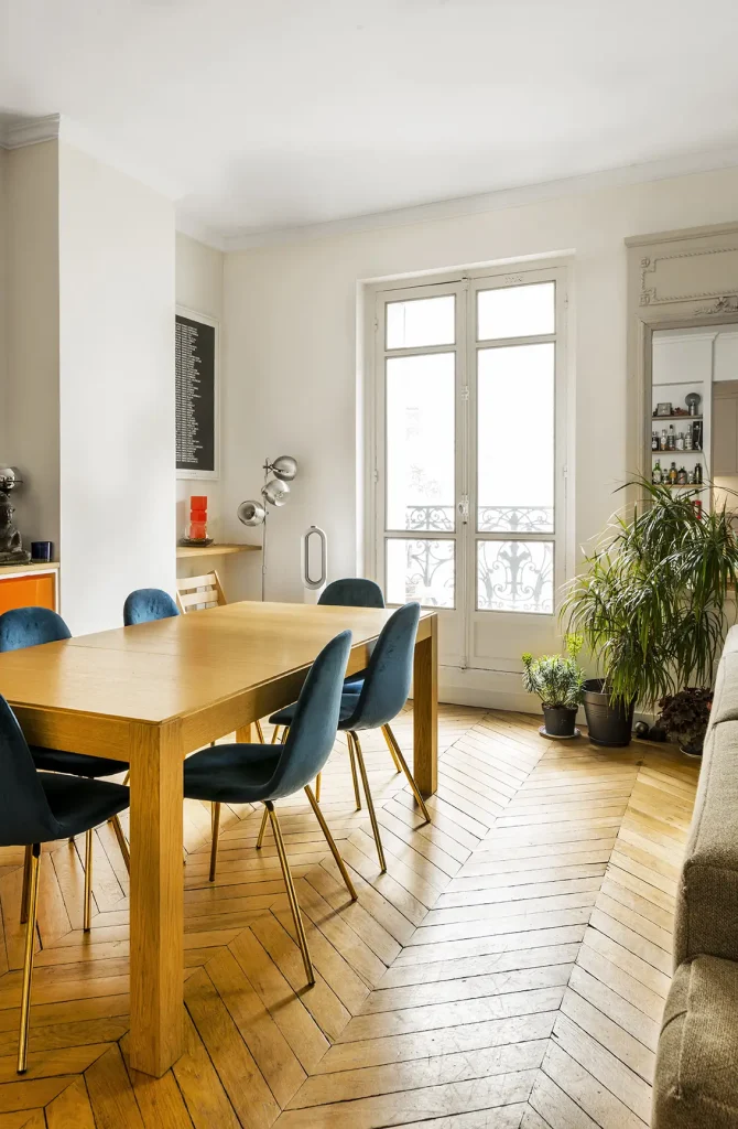 Salon d'un appartement rénové, rangement, grande table et chaise bleue